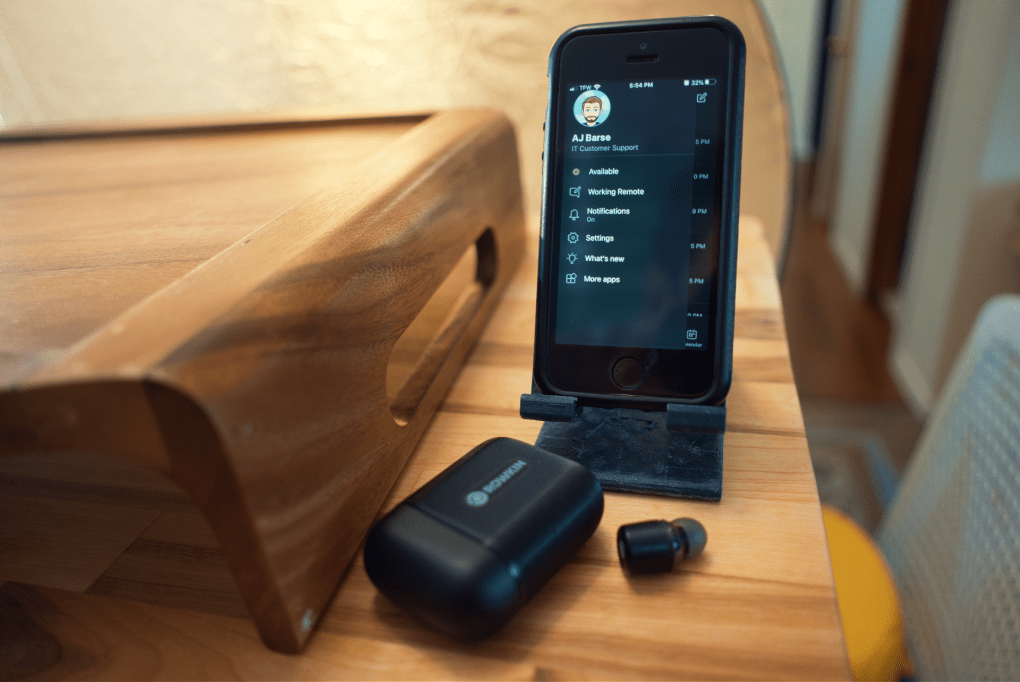 an iphone with black Rowkin earbuds on a wood table