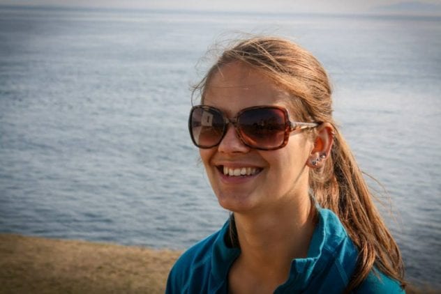 Shannon Buckham smiling and wearing sunglasses at the beach with shore and water in the background.