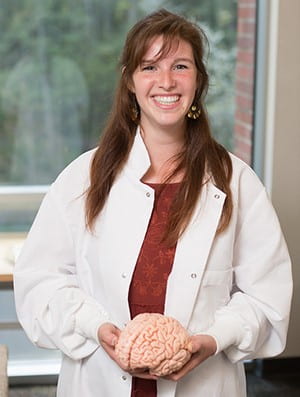 Anna Marie Yanny wearing a lab coat and holding a brain model