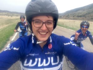Selfie of team member riding with people behind and to the side of her.