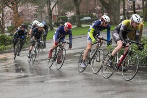 Pack of riders come around a turn on a grey, wet day