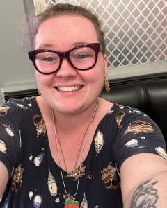 Selfie of Violet Smith, a fair skinned person, wearing glasses, smiling.