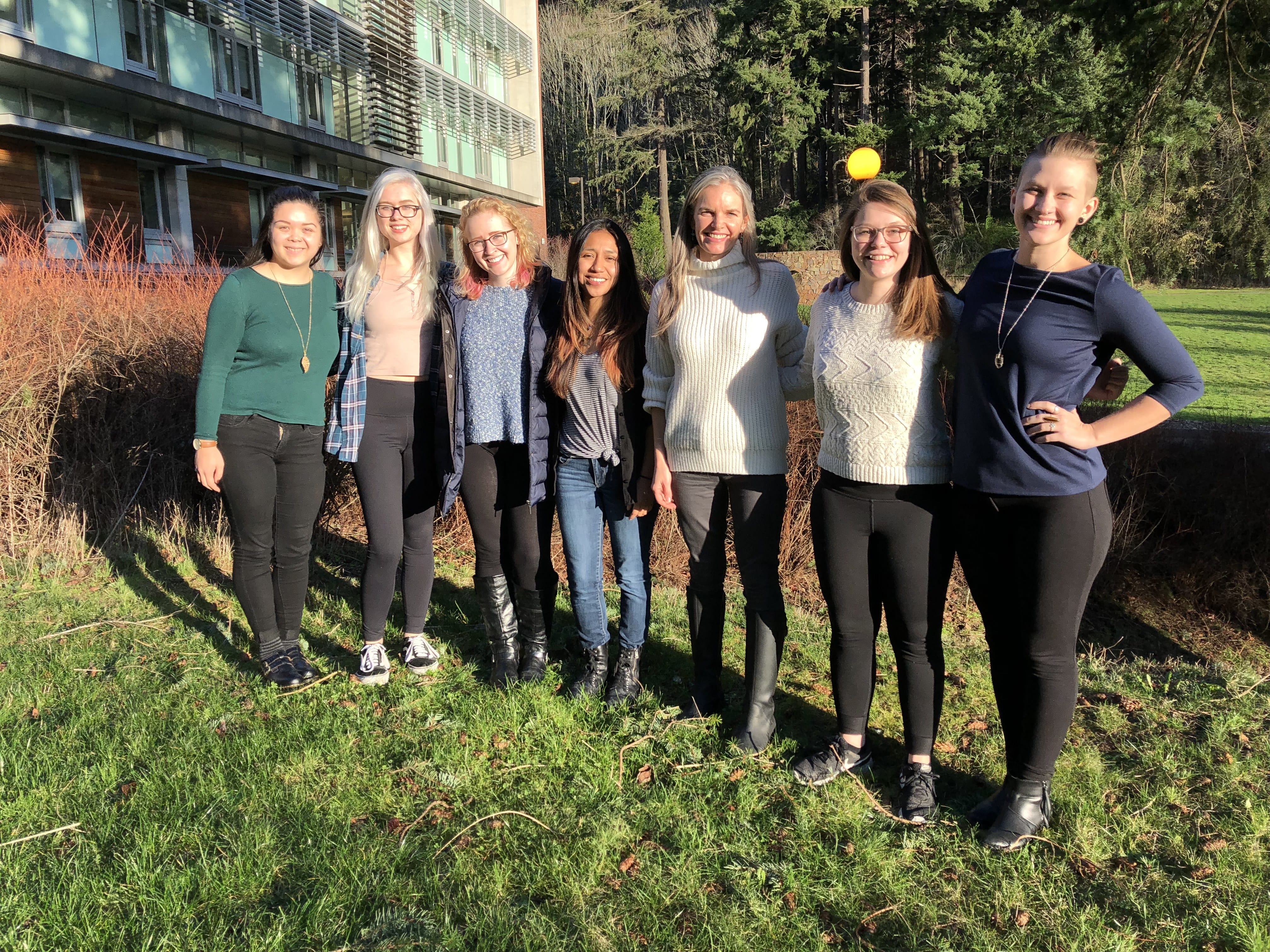 Seven women pose outside Academic West on sunny day