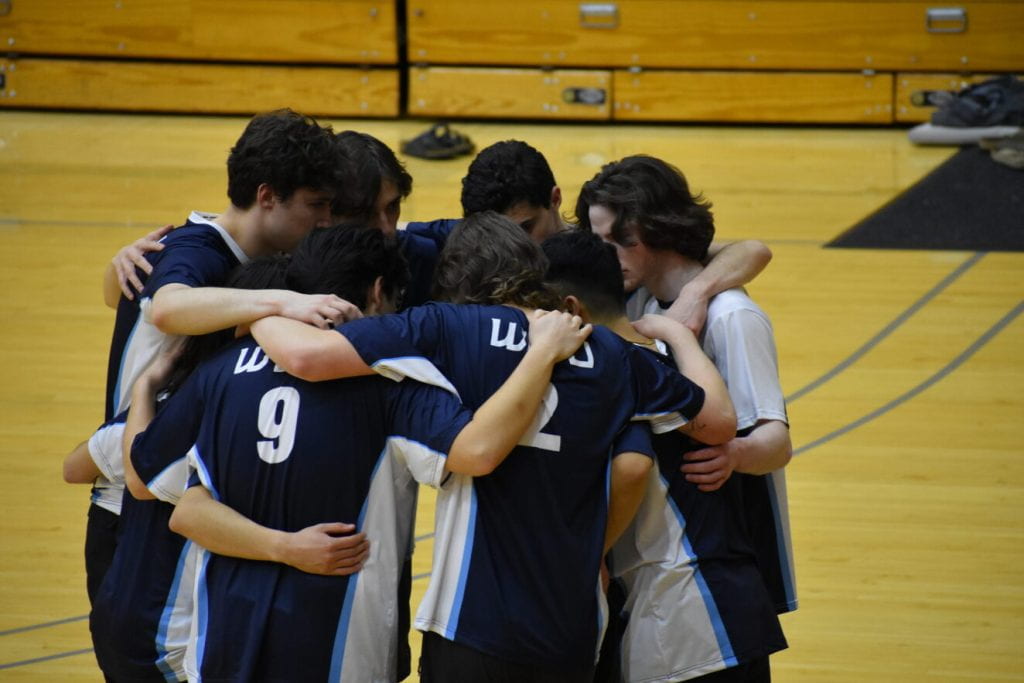 WWU Men's Volleyball Team in a huddle on the court