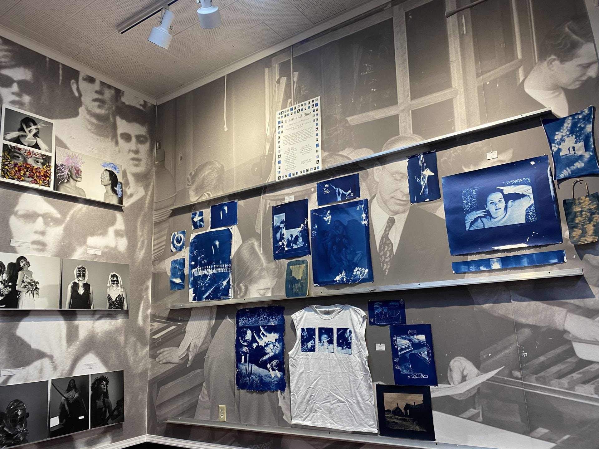 Several cyanotype pieces on display including a large white t-shirt and some black and white photo prints