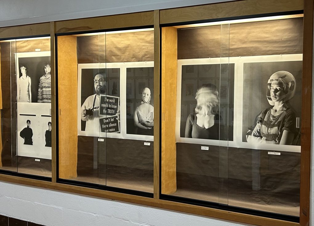 An image of large photographs behind glass cases. Six self portraits.