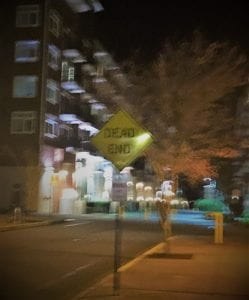 a blurry street with Dead End sign