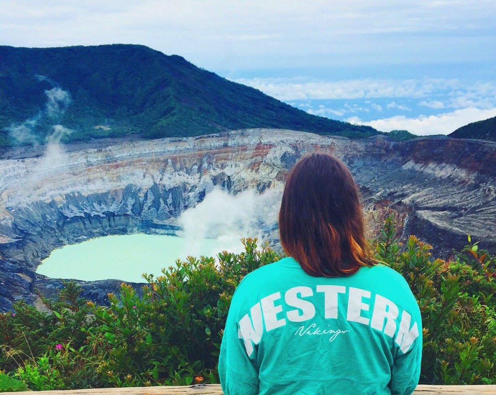 Student wearing a green Western shirt looks at the Poás Volcano in Costa Rica.