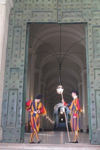 Men in striped outfits guard a large doorway