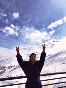 Student poses with a snowy ski area in background