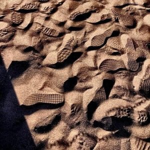 Footprints of several shoes shown in sand