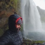 Student wearing cold weather clothes by a waterfall