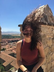 Wind catches a student's hair over a Mediterranean town