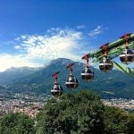 Spherical gondolas overlook a large city and distant mountains