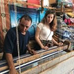 A man uses a loom to create woven fabrics