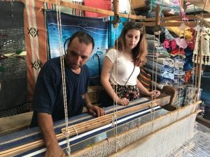 A man uses a loom to create woven fabrics