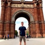 Student stands in front of a red brick arch