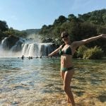 Student in swimsuit poses in front of waterfall