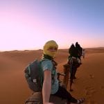 A student rides a camel through a desert setting