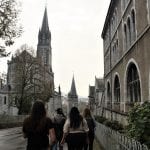 Student group walks down a street with Gothic styled buildings