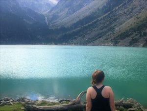 Student facing light green colored lake, with hills in background