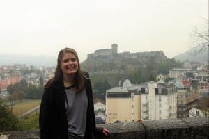 Student poses with a castle on a hill in background