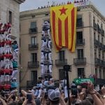 A crowd watches acrobatic demonstrations, while a Catalan flag hangs from a building