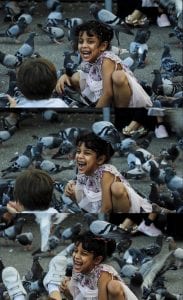 A smiling girl plays while surrounded by birds