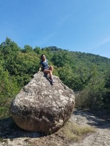 A student poses on a large boulder