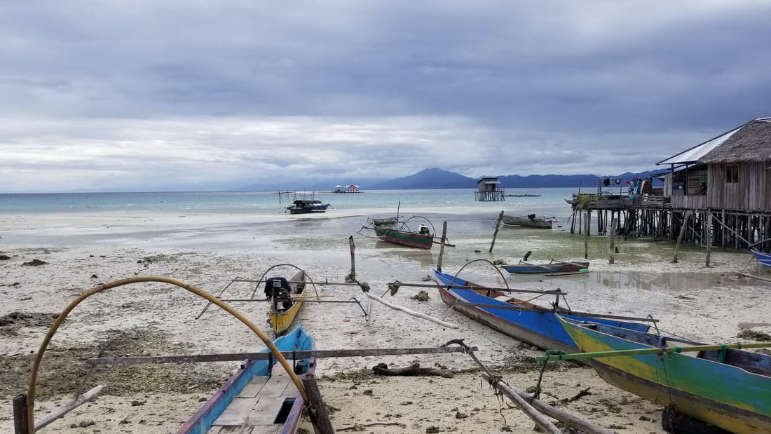A view of small boats beached at the edge of the water in Sulawesi.
