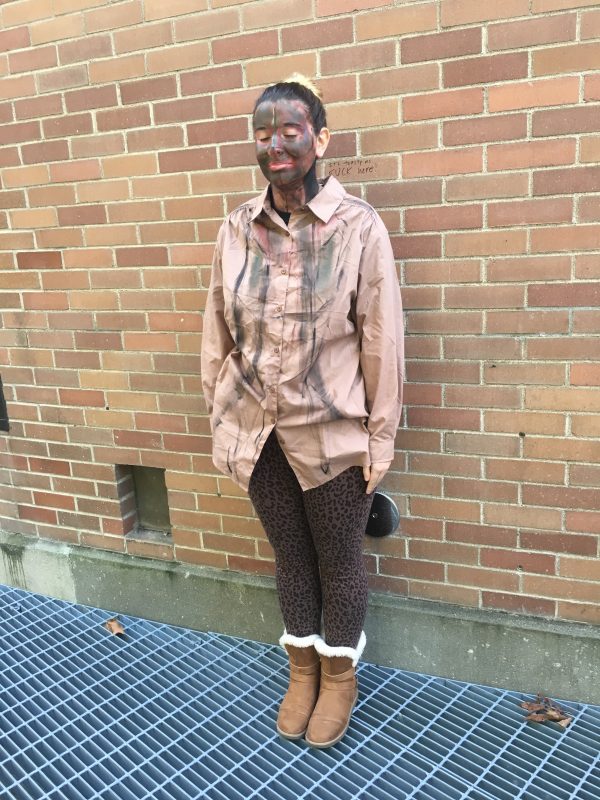 Model standing with brown clothing and brown face paint in front of brick to look like scpeter.