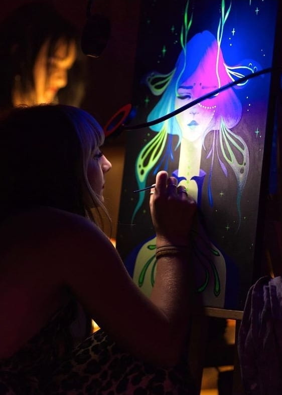 nat painting on a black canvas with bright neon colors illuminated by a black light